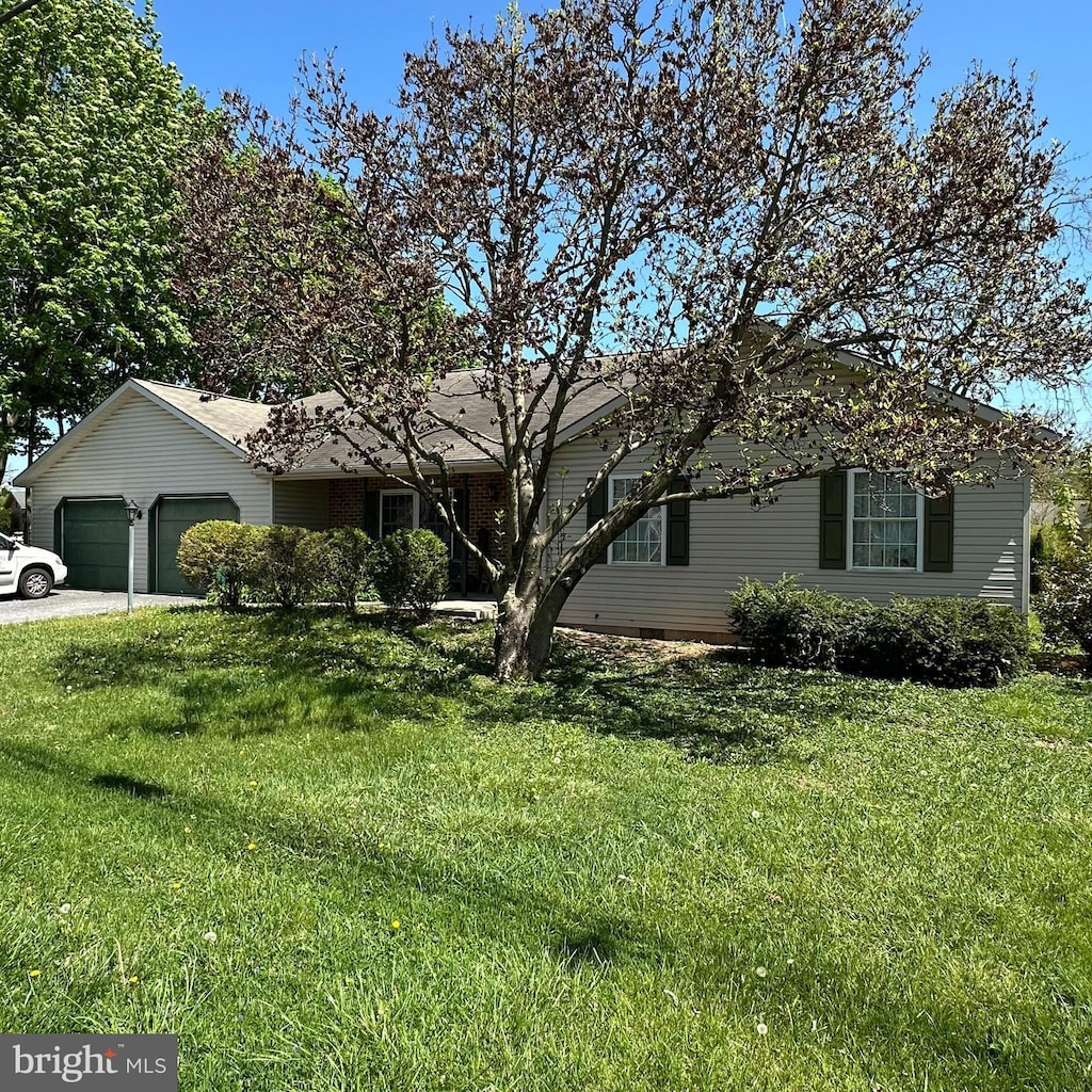 ranch-style house featuring a garage, a front lawn, and driveway