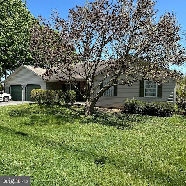 ranch-style house featuring a garage, a front lawn, and driveway