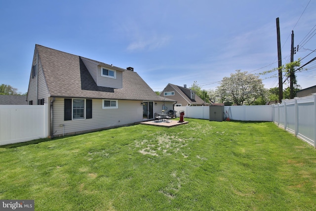 back of house featuring a yard, a chimney, a fenced backyard, and roof with shingles