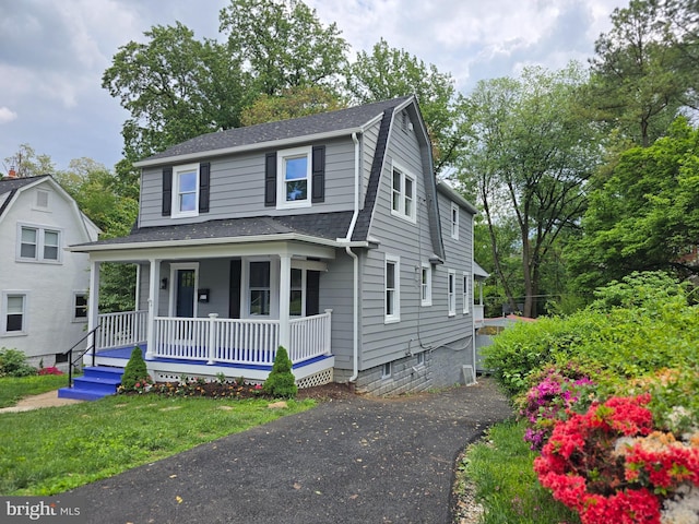 view of front facade with a porch, a shingled roof, and a gambrel roof