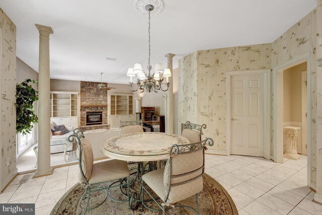 dining room with a fireplace, baseboards, wallpapered walls, ornate columns, and ceiling fan with notable chandelier