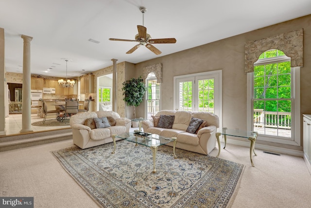 living area featuring light carpet, a healthy amount of sunlight, and ceiling fan with notable chandelier