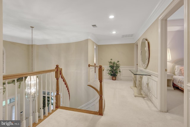 corridor with visible vents, crown molding, a decorative wall, recessed lighting, and carpet
