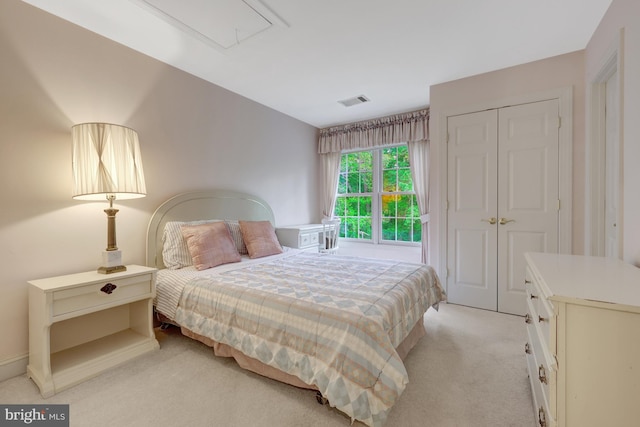 bedroom featuring visible vents, light colored carpet, attic access, and a closet