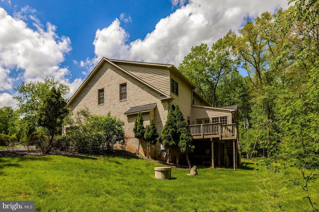back of property featuring a lawn, a deck, and brick siding