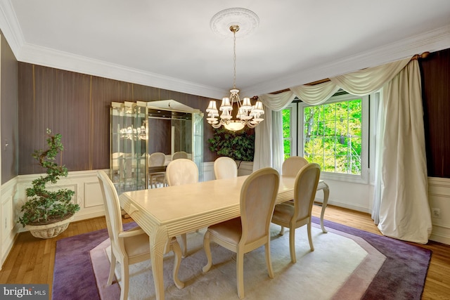 dining area featuring crown molding, light wood finished floors, and a chandelier