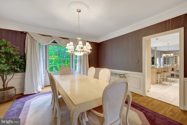 dining area with ornamental molding, wood finished floors, and a notable chandelier