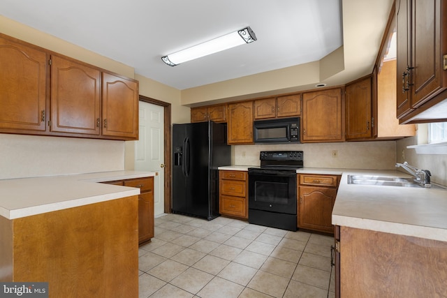 kitchen featuring brown cabinetry, a sink, light countertops, black appliances, and light tile patterned flooring