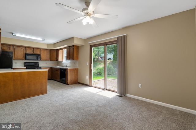 kitchen featuring brown cabinetry, baseboards, light colored carpet, light countertops, and black appliances