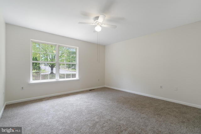 empty room featuring a ceiling fan, baseboards, visible vents, and carpet