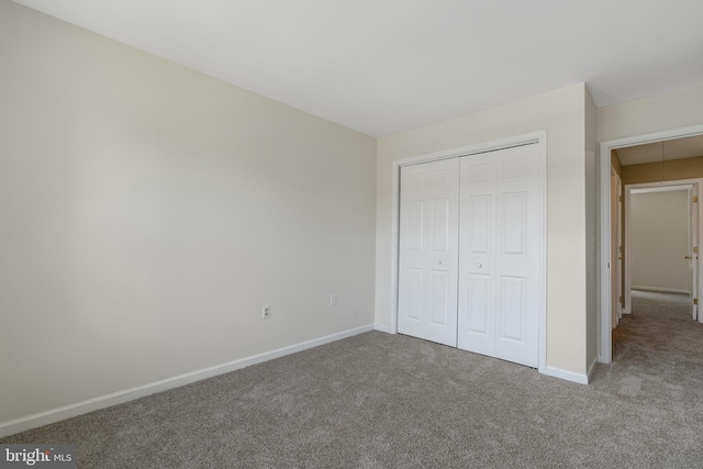 unfurnished bedroom featuring a closet, baseboards, carpet flooring, and attic access