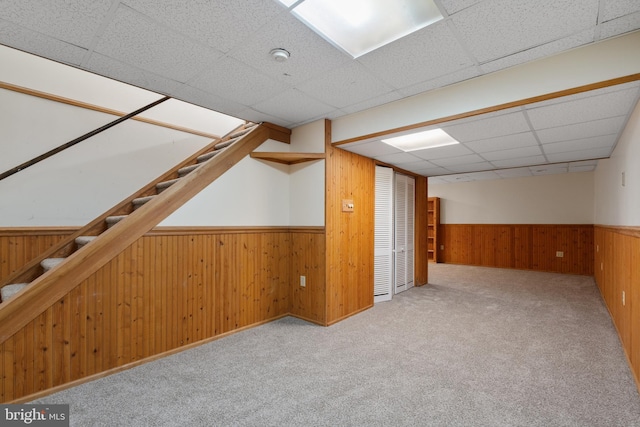 additional living space featuring carpet, wainscoting, wood walls, and stairway