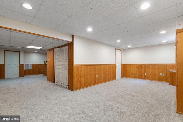 finished basement with visible vents, carpet, a wainscoted wall, and a drop ceiling