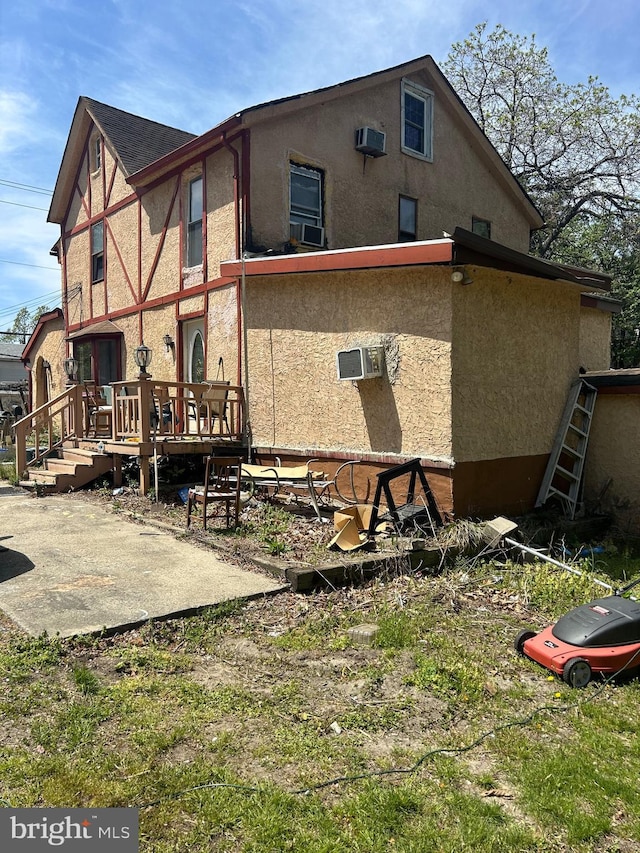 back of house with stucco siding, a wooden deck, and a patio