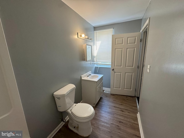 bathroom featuring toilet, baseboards, vanity, and wood finished floors