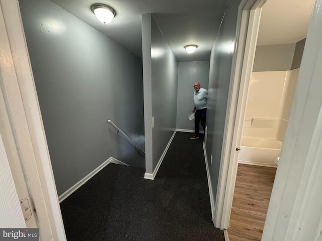 corridor featuring an upstairs landing and baseboards
