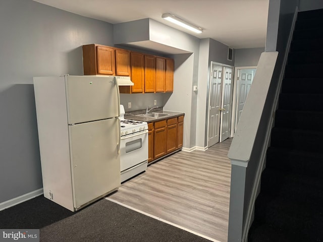 kitchen with white appliances, range hood, a sink, brown cabinets, and baseboards