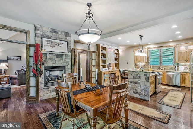 dining room with a fireplace, dark wood-type flooring, and recessed lighting