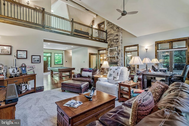 living area featuring wood finished floors, a ceiling fan, high vaulted ceiling, a stone fireplace, and billiards