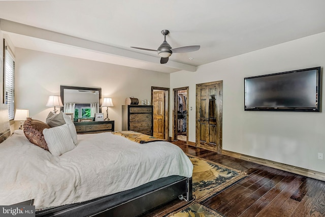 bedroom with a closet, wood finished floors, a spacious closet, a ceiling fan, and baseboards