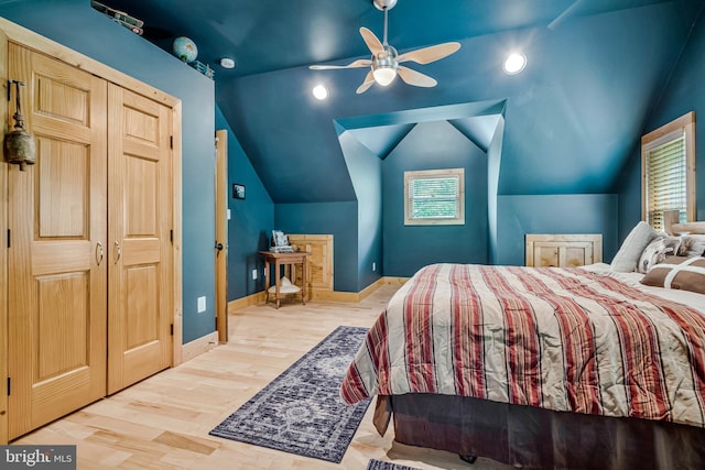 bedroom with vaulted ceiling, wood finished floors, baseboards, and multiple windows