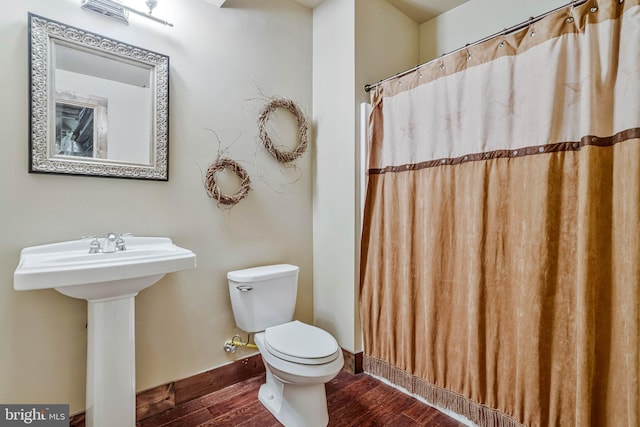 bathroom featuring toilet, a shower with shower curtain, a sink, and wood finished floors