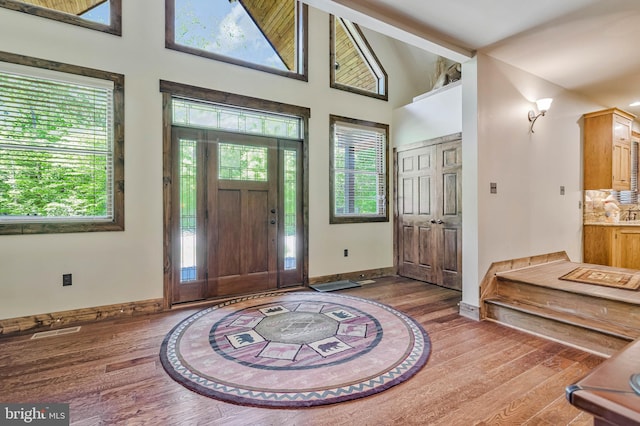 foyer featuring visible vents, baseboards, a healthy amount of sunlight, and wood finished floors