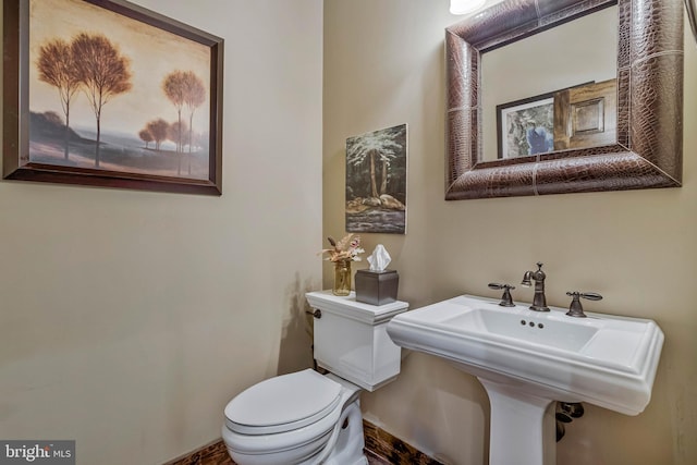bathroom with a sink, toilet, and baseboards
