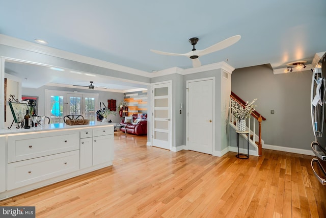 kitchen with french doors, light wood-style flooring, a ceiling fan, baseboards, and white cabinetry