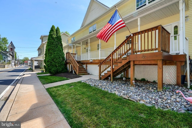 exterior space featuring a yard, covered porch, and stairs