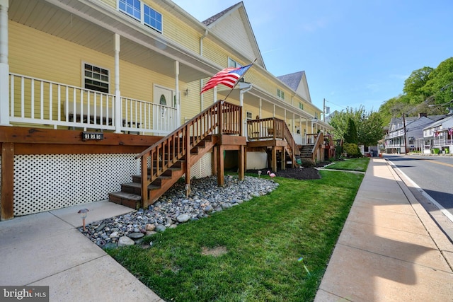 exterior space featuring a lawn, stairway, and a porch