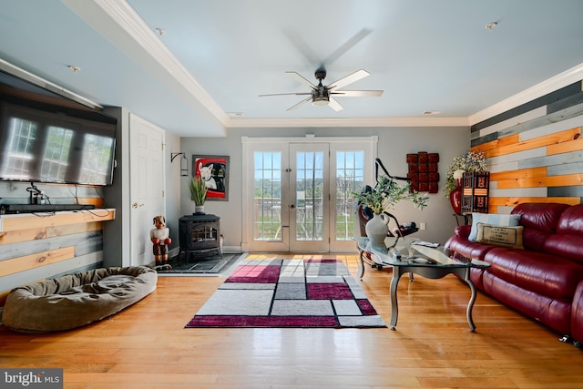 living room featuring ceiling fan, french doors, a wood stove, wood finished floors, and ornamental molding