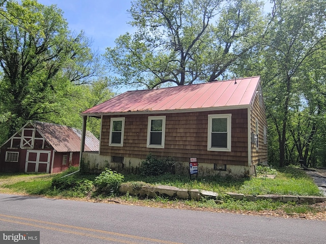 view of side of property featuring an outbuilding, a storage shed, a standing seam roof, and metal roof
