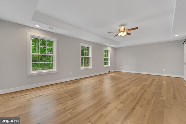unfurnished room with a raised ceiling, recessed lighting, baseboards, light wood-type flooring, and visible vents