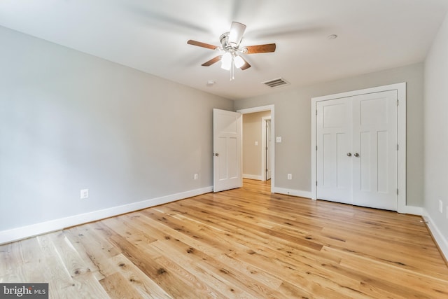 unfurnished bedroom with visible vents, a closet, baseboards, a ceiling fan, and light wood-style flooring