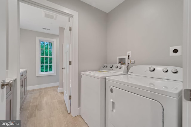 laundry room with laundry area, visible vents, baseboards, light wood-style flooring, and washer and dryer