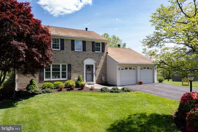 colonial inspired home with a garage, roof with shingles, a front lawn, and aphalt driveway
