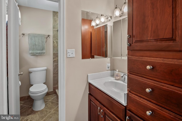 bathroom featuring toilet, tile patterned floors, a tile shower, and vanity
