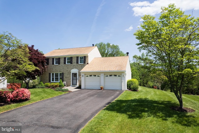 colonial-style house with a garage, a front lawn, and aphalt driveway
