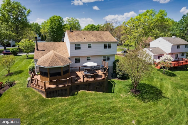 back of house with roof with shingles, a yard, and a deck