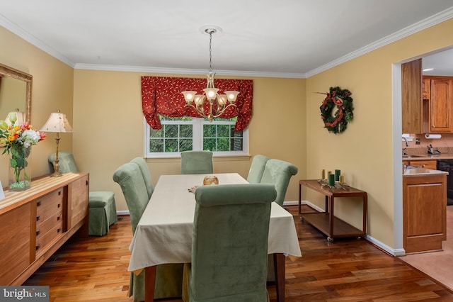 dining space with crown molding, an inviting chandelier, and wood finished floors
