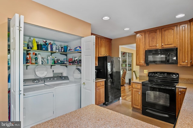 kitchen featuring washing machine and clothes dryer, brown cabinets, light stone counters, black appliances, and recessed lighting