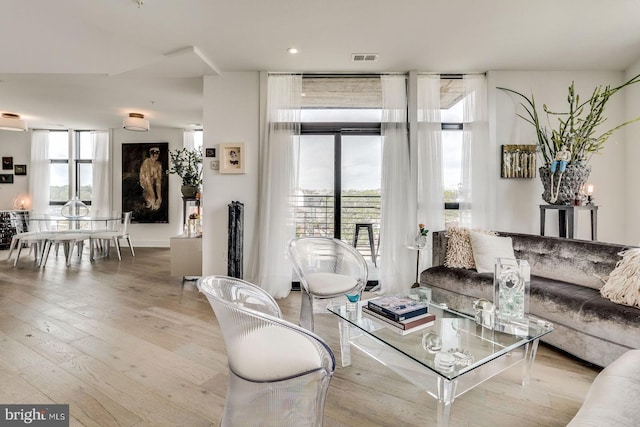 living room with wood-type flooring, visible vents, and a wealth of natural light