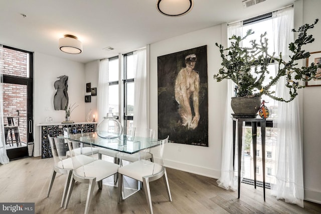 dining room featuring floor to ceiling windows, wood finished floors, and visible vents
