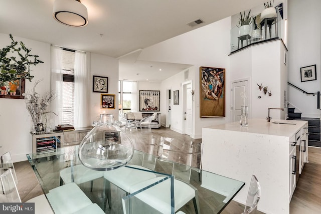 dining area with stairs, baseboards, visible vents, and wood finished floors