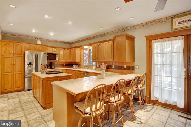 3401 Eisenbrown Rd, Reading, PA 19605 - kitchen featuring a peninsula, a kitchen island, tile counters, tasteful backsplash, and stainless steel appliances