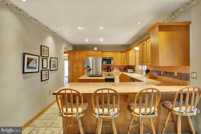3401 Eisenbrown Rd, Reading, PA 19605 - kitchen with appliances with stainless steel finishes, baseboards, tile countertops, and a peninsula