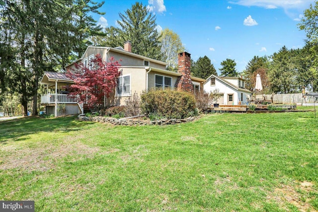 3401 Eisenbrown Rd, Reading, PA 19605 - back of property featuring a lawn, stucco siding, a chimney, and a deck