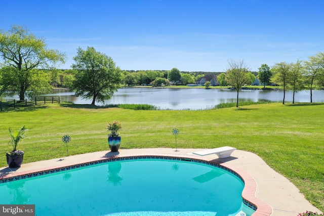 pool featuring a water view, fence, and a yard