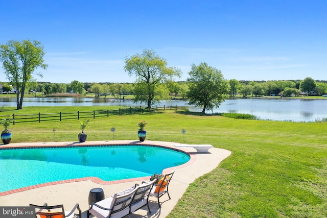 pool with fence, a diving board, a water view, and a yard